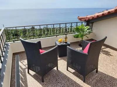 a balcony with chairs and a table and the ocean at Tabua Village Madeira Suite 5 Nature Lovers in Ribeira Brava