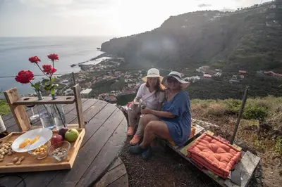 two women sitting on a bench with a table of food at Tabua Village Madeira Suite 5 Nature Lovers in Ribeira Brava