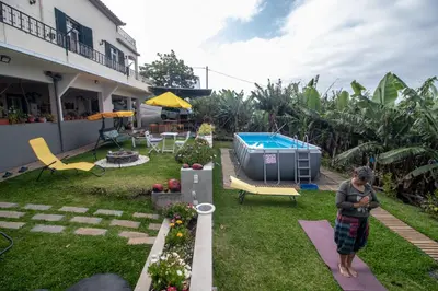 a woman standing in the yard of a house with a pool at Tabua Village Madeira Suite 5 Nature Lovers in Ribeira Brava