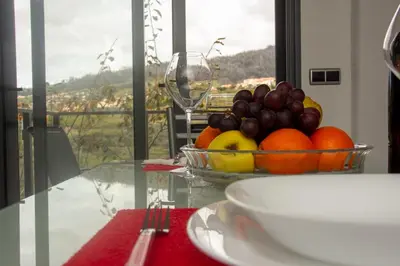 a bowl of fruit on a glass table with a wine glass at Amoreira House in Calheta