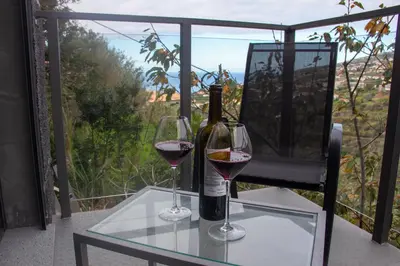 a bottle of wine and two glasses on a table at Amoreira House in Calheta