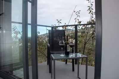 a table with two glasses of wine on a balcony at Amoreira House in Calheta