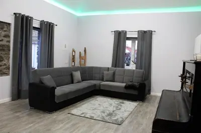 a living room with a gray couch and windows at Cottage Quinze & Apartment with Swimming pool in Ponta Delgada