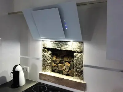 a kitchen with a stone fireplace with a hood at Cottage Quinze & Apartment with Swimming pool in Ponta Delgada