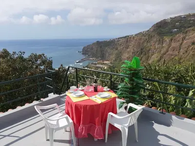 a table and chairs on a balcony with the ocean at Tabua Village Madeira Suite 6 Adventure with Ocean View in Ribeira Brava