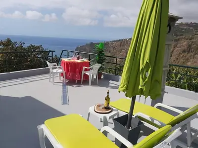 a patio with a table and a green umbrella at Tabua Village Madeira Suite 6 Adventure with Ocean View in Ribeira Brava