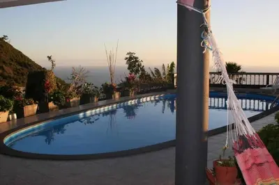a large swimming pool with a view of the ocean at Arcos Grand Suites with pool in Calheta