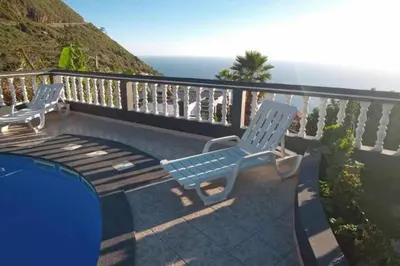two blue chairs sitting on a balcony overlooking the ocean at Arcos Grand Suites with pool in Calheta