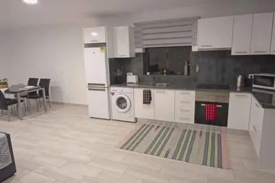 a kitchen with white cabinets and a washer and dryer at Arcos Grand Suites with pool in Calheta