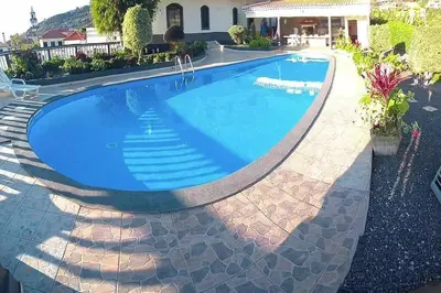 a swimming pool with blue water in a yard at Arcos Grand Suites with pool in Calheta