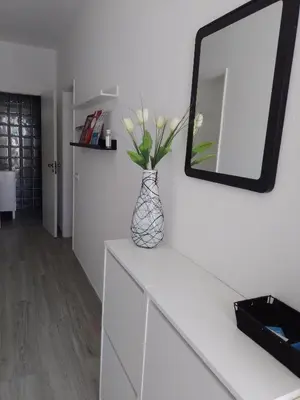 a vase with flowers on a white dresser with a mirror at Casa Florival in Burgau