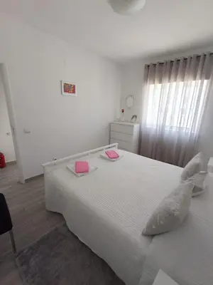 a white bedroom with a large white bed with two pink towels at Casa Florival in Burgau