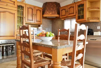 a kitchen with wooden cabinets and a table with a bowl of fruit at Casa da Piedade, a Home in Madeira in Ponta do Sol