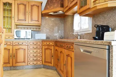 a kitchen with wooden cabinets and a dishwasher at Casa da Piedade, a Home in Madeira in Ponta do Sol