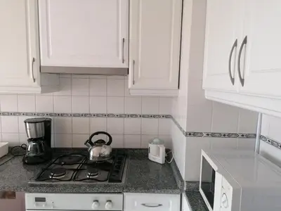 a kitchen with white cabinets and a tea kettle on the stove at Lido Funchal Apartment balcony sea view in Funchal