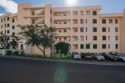 a large building with cars parked in a parking lot at Garajau IV by An Island Apart in Caniço