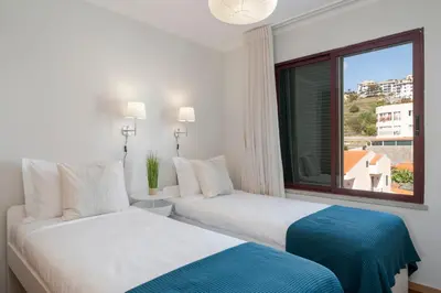 two beds in a hotel room with a window at Garajau IV by An Island Apart in Caniço