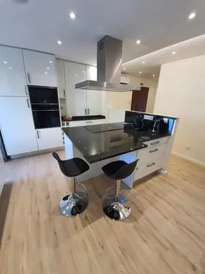 a kitchen with a black counter and two bar stools at Sunrise Glances & Free Parking in Funchal