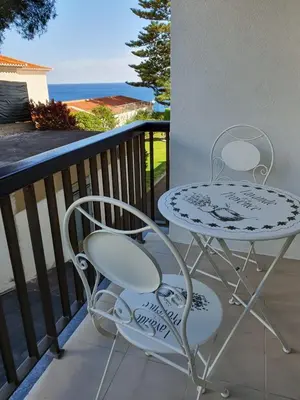 a table and chairs on a balcony with the ocean at Sunrise Glances & Free Parking in Funchal
