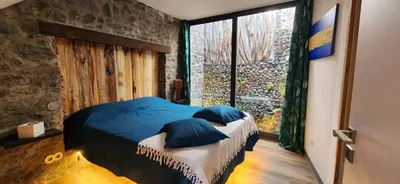 a bedroom with a bed with blue pillows and a window at Casas Floeca in Ponta do Sol