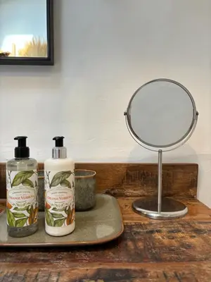 a mirror and two bottles on a wooden table at Casa da Oliveira - Bordeira in Bordeira