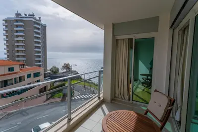 a balcony with a chair and a view of the ocean at FLH Funchal Balcony Apartment with Sea View in Funchal