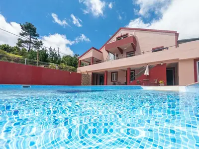a swimming pool in front of a house at Spacious apartment with pool in Prazeres - 150m² in Campanário
