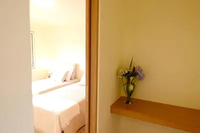 a mirror reflecting a bedroom with a bed and a vase with flowers at Modern apartment in Prazeres with shared pool, 150 m² in Campanário