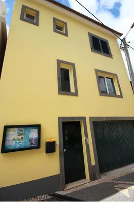 a yellow house with a black door and windows at The Yellow House in Paul do Mar