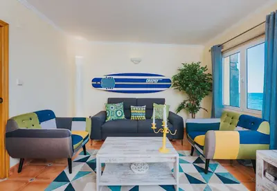 a living room with a couch and a surfboard on the wall at The Yellow House in Paul do Mar