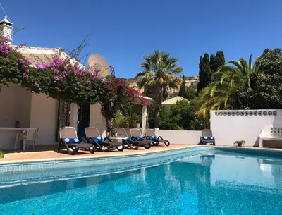 a swimming pool with chairs and purple flowers next to a building at Charming Villa with Heated Pool near Sandy Beach, Hiking, Golf and Wineries in Luz