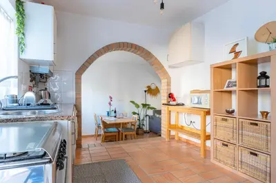 a kitchen with an archway and a dining room with a table at Casa Oceano-Ave do Mar in Raposeira