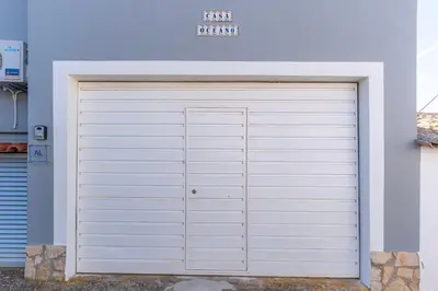 a white garage door in front of a blue building at Casa Oceano-Ave do Mar in Raposeira