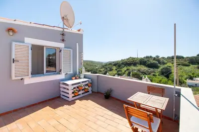 a balcony of a house with a table and a window at Casa Oceano-Mar a vista in Raposeira