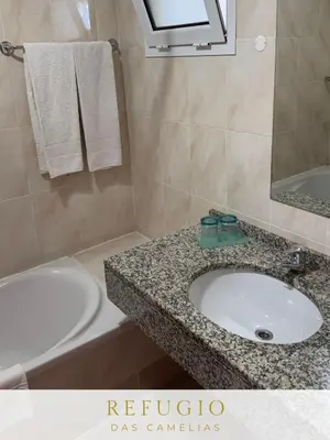 a bathroom with a sink and a toilet and a tub at Refúgio das Camélias in Santana