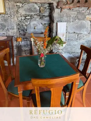 a wooden table with a vase of flowers on it at Refúgio das Camélias in Santana