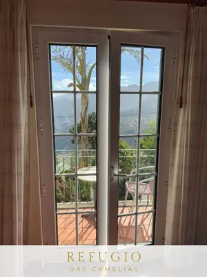 an open door with a view of a tree at Refúgio das Camélias in Santana