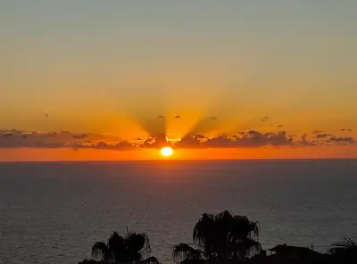 a sunset over the ocean with birds in the sky at Bluegreen in Arco da Calheta