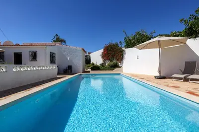 a swimming pool with an umbrella next to a house at Villa Mirembe in Luz