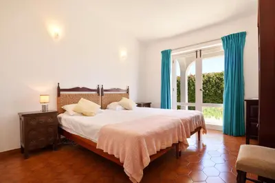 a bedroom with a large bed with blue curtains and a window at Villa Mirembe in Luz