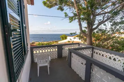 a balcony with a chair and a view of the ocean at Avó Lucindinha House - Porto Moniz in Porto Moniz