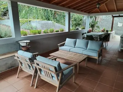 a screened porch with chairs and a table and a table at Avó Lucindinha House - Porto Moniz in Porto Moniz
