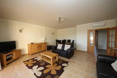 a living room with a couch chair and a television at Acácias, spacious apartment with sea view in Luz