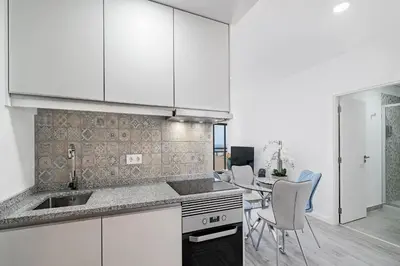 a kitchen with white cabinets and a table with chairs at Santa Luzia I by An Island Apart in Funchal