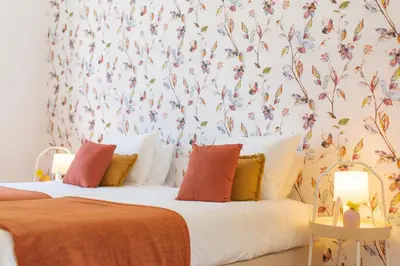 a bedroom with two beds with a floral wallpaper at Casa do Bago in São Vicente