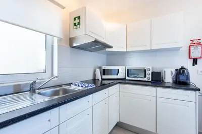 a kitchen with white cabinets and a sink and microwave at Mariners (5) - Bright and stylish apartment - walk to the beach in Luz