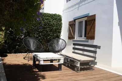 a patio with two chairs and a bench and a window at Casa Boa Onda in Sagres