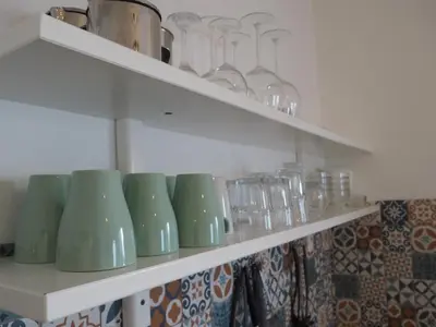 a row of green vases and glasses on shelves at Casa Boa Onda in Sagres