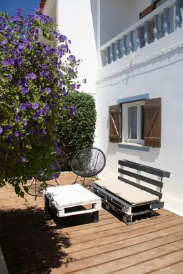 a patio with a bench and a bush with purple flowers at Casa Boa Onda in Sagres