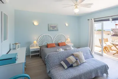 a bedroom with a bed and a couch and a patio at Mariners (3) - Bright and stylish apartment - 2 minute walk to the beach in Luz
